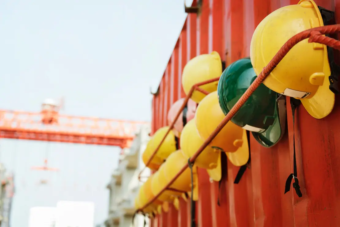 Photograph of red and green construction hats hanging in a row.