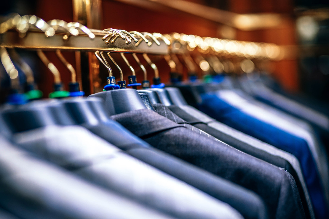 Photograph of row of suits hung up in retail shop