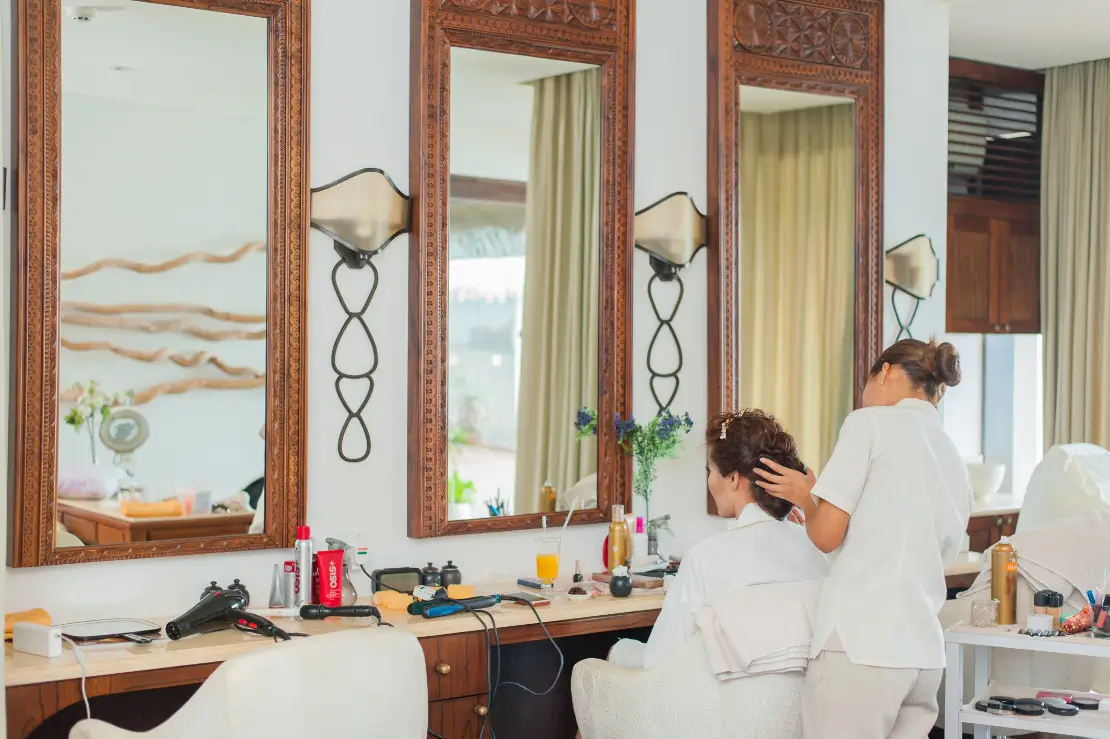 Photograph woman getting her hair styled in a salon by a female hair dresser.